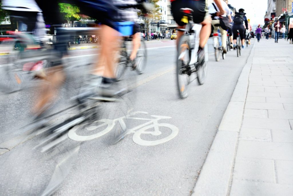 many cyclists riding in an urban area with a dedicated bike lane that prevents dooring collisions