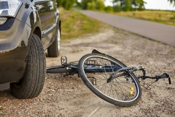A bicycle leans against a parked car, highlighting the importance of cyclist safety in traffic.