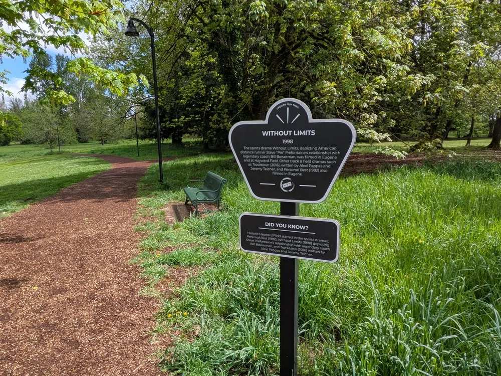 A park sign indicating a path, with a wooden bench visible nearby for resting.