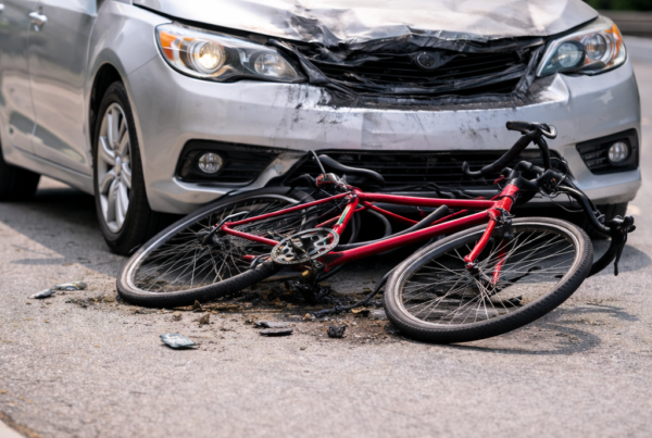 A damaged car with visible scratches and dents caused by a bicycle collision parked on a city street.
