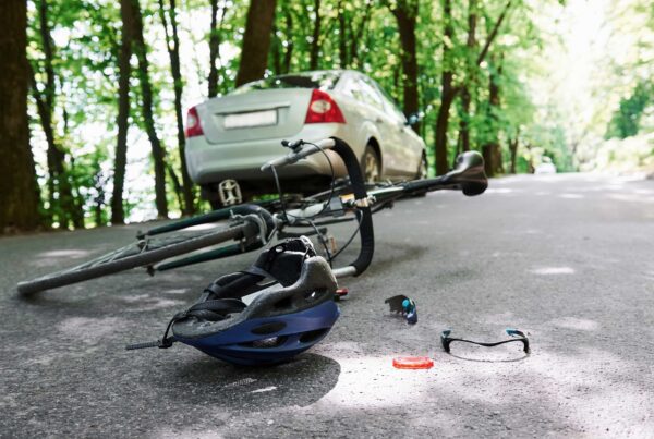 A bicycle and helmet are on the ground beside a parked car, suggesting a recent ride or potential accident.