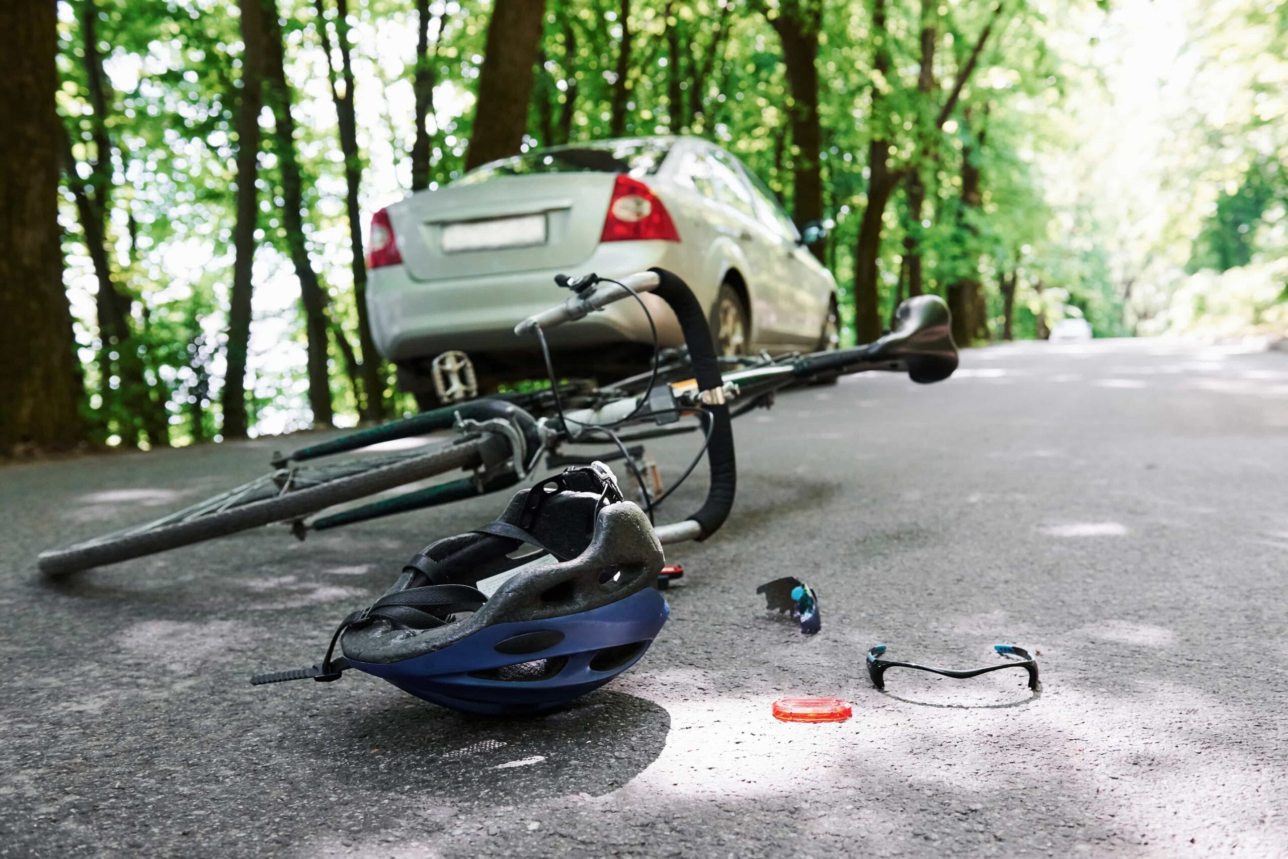 A bicycle and helmet are on the ground beside a parked car, suggesting a recent ride or potential accident.